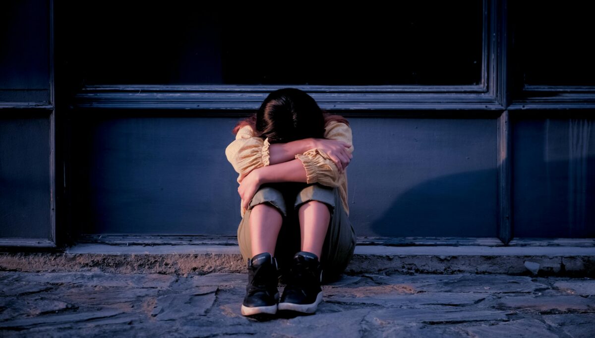 Girl with head down, sitting on floor.